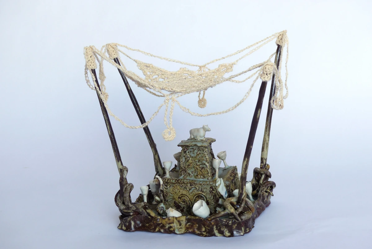 Groupe sacré en terre, une vache trone au centre de la pièce, des coupes sont éparpillées autour, des piquets aux extrémités de la pièce accueillent une voilure en crochet