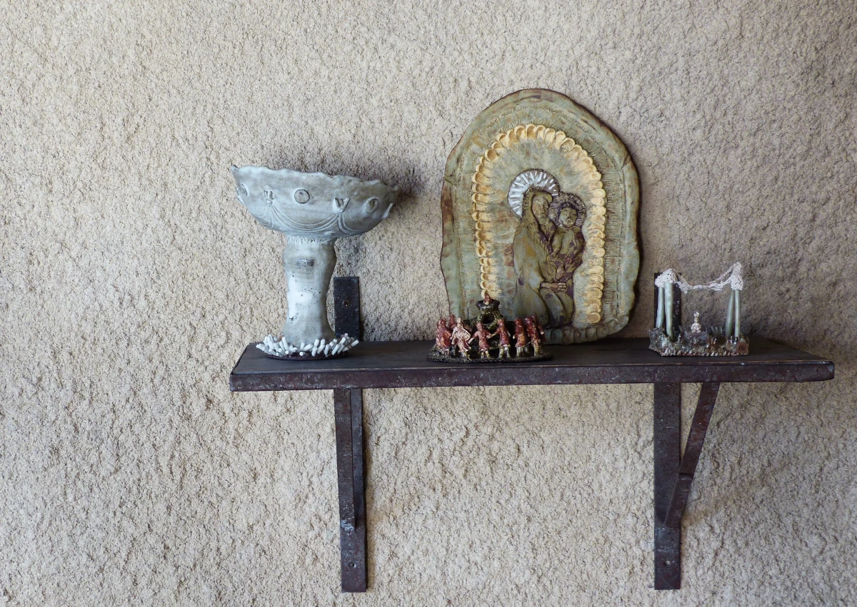 Ensemble de pièces en céramique posé sur une étagère : callice, muraux, groupe sacré
