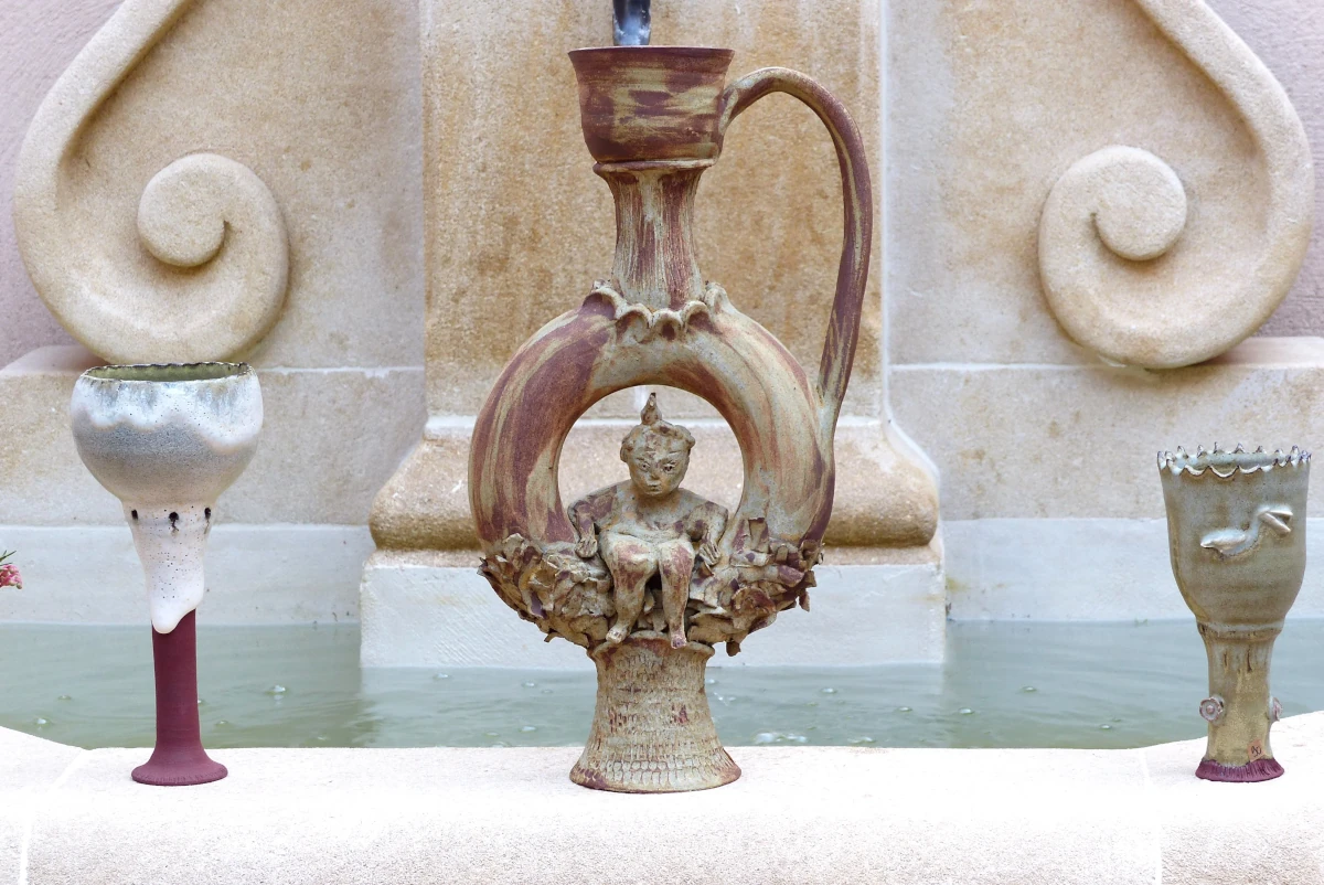 Gourde en terre avec une coupe de chaque coté, posé sur une fontaine