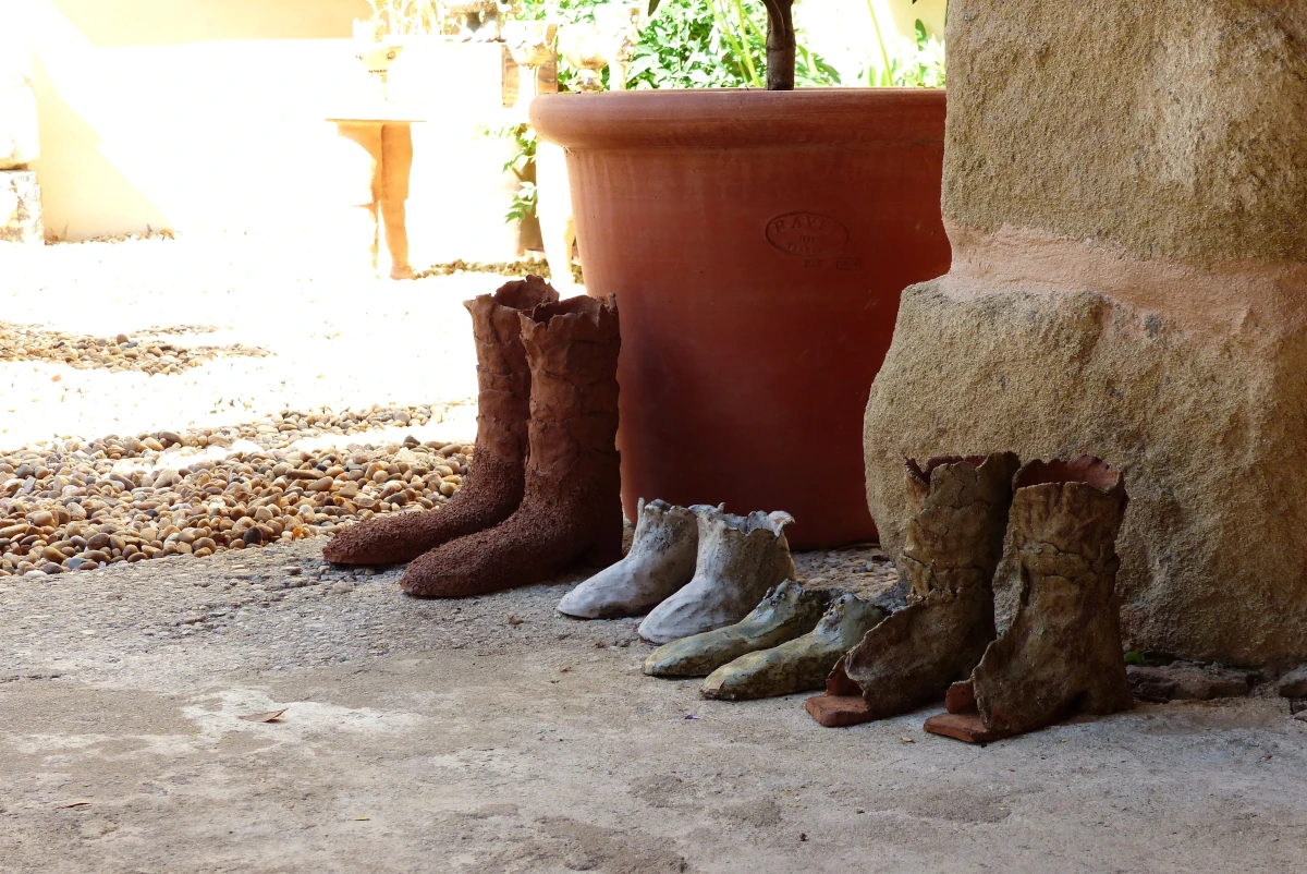 Ensemble de bottes, chaussures, chausson, sculptures en terre posé au sol